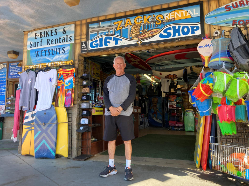 Mike Ali, the owner of Zack's shop near the Huntington Beach pier, waits for customers in Huntington Beach, Calif., Sunday. Oct. 10, 2021. He says business has been hurting since an offshore pipeline leaked oil into the waters off Huntington Beach. People come in to rent bikes and food, and his business has plummeted without surf lessons and event catering. The water has been closed to surfing and swimming for a week since the spill. (AP Photo/Amy Taxin)