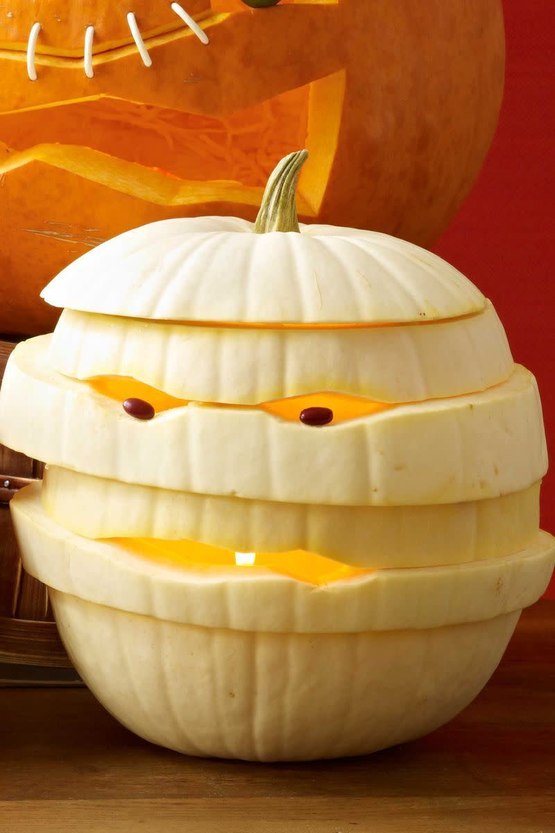<p>Stack layers of a cut up pumpkin to create a mummy wrapped-like appearance. Beady bean eyes will send trick-or-treaters running in fear.<strong><br></strong></p><p><strong>Make the Mummy Pumpkin:</strong> Cut off the top one quarter of the pumpkin and scoop out the seeds. Cut pumpkin horizontally all the way around, starting 1" to 2" below the opening. Repeat 4 to 6 times until you've carved the whole pumpkin into 1" to 2" circles all the way around (don't worry about making your cuts particularly straight). Separate the pieces. Keeping the top and bottom pieces the same, restack the others in a different order. Rotate the pieces until you get a shape you like, enlarging the carvings for eyes or mouth. Starting from the bottom, lift each level of pumpkin, insert 3 to 4 toothpicks onto the level below, then press down to secure in place. Repeat until entire pumpkin is held together. Place beans into eye holes, securing with half-toothpicks if necessary.</p>