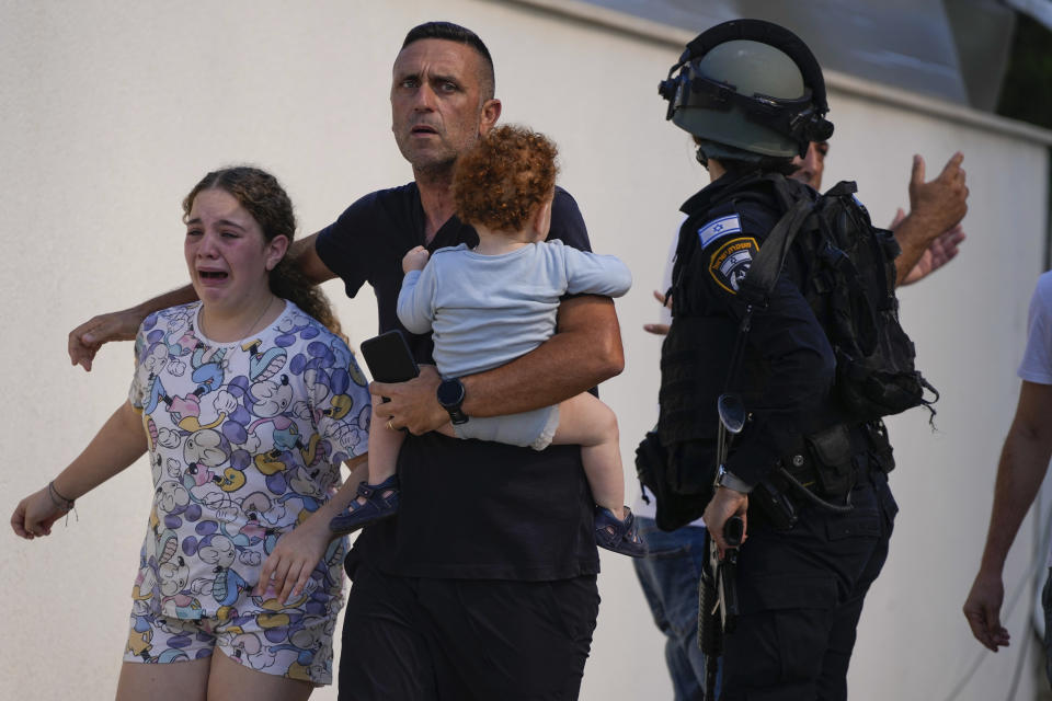 FILE - Israeli police officers evacuate a family from a site hit by a rocket fired from the Gaza Strip, in Ashkelon, southern Israel, Saturday, Oct. 7, 2023. The rockets were fired as Hamas announced a new operation against Israel. (AP Photo/Tsafrir Abayov, File)