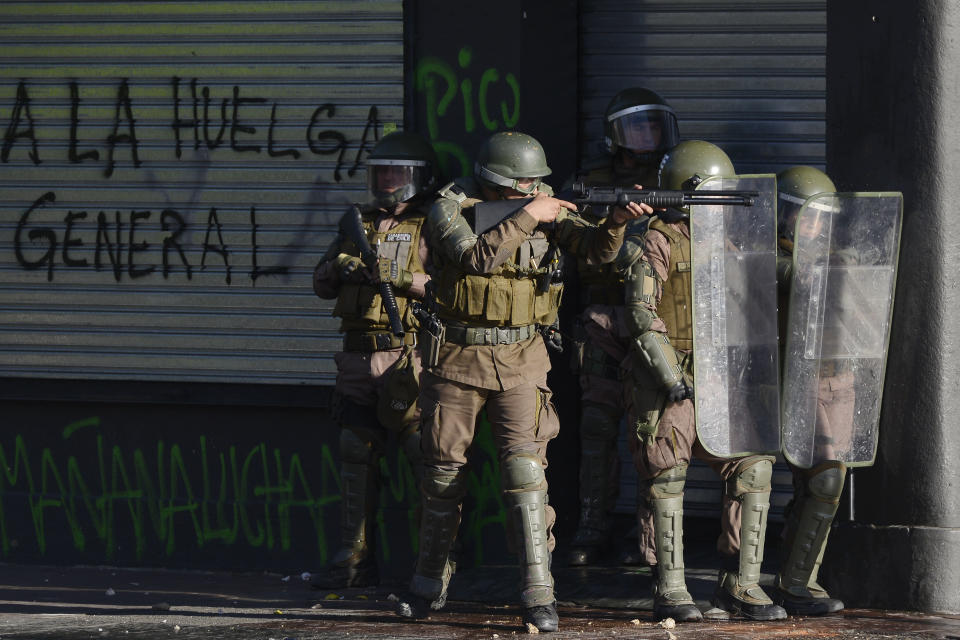 Police aim a shotgun during clashes with anti-government protesters in Valparaiso, Chile, Friday, Oct. 25, 2019. A new round of clashes broke out Friday as demonstrators returned to the streets, dissatisfied with economic concessions announced by the government in a bid to curb a week of deadly violence.(AP Photo/Matias Delacroix)