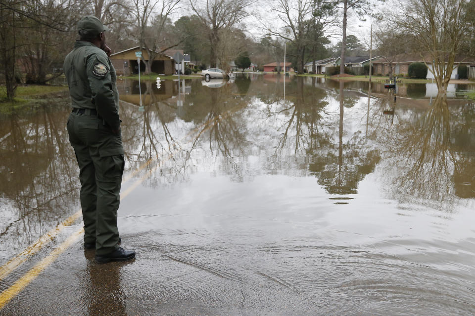 A Mississippi Department of Wildlife, Fisheries and Parks lawman, observes the swirling Pearl River floodwaters drain from North Canton Club Circle in Jackson, Miss., Tuesday afternoon, Feb. 18, 2020. Officials have limited entry to the flooded neighborhoods as they have warned residents about the contamination of the receding waters and the swift currents. (AP Photo/Rogelio V. Solis)