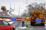 A woman talks with a gritter driver working on a closed road in Spittal of Glenshee, Scotland.