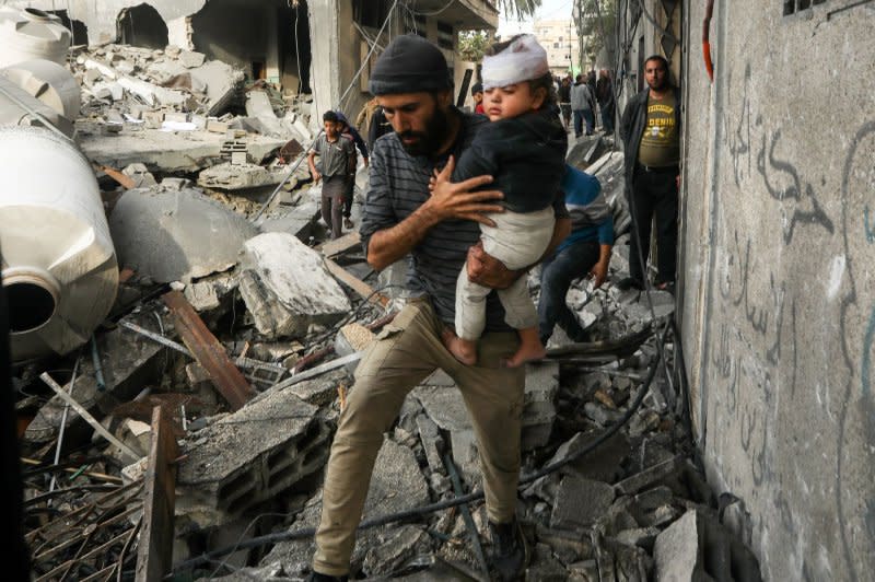 A Palestinian man evacuates a wounded child after an Israeli air strike on the Ali ben Abi Taleb mosque in Rafah in the southern Gaza Strip on Wednesday. Also in Rafah, a residential building was leveled, as well, and 10 Palestinian fatalities were reported. Photo by Ismael Mohamad/UPI