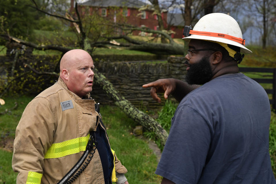 Capt. Patrick Staudenheimer, left, with the Anchorage Middletown Fire Department, speaks with an employee of the Louisville Gas and Electric company informing him of possible gas leaks following severe storms in Prospect, Ky., Tuesday, April 2, 2024. (AP Photo/Timothy D. Easley)