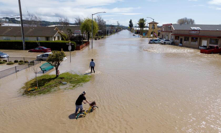 An aerial view shows people making their way around a flooded neighborhood in the unincorporated community of Pajaro in Watsonville, California on March 11, 2023. - Residents were forced to evacuate in the middle of the night after an atmospheric river surge broke the Pajaro Levee and sent flood waters flowing into the community. (Photo by JOSH EDELSON / AFP) (Photo by JOSH EDELSON/AFP via Getty Images)