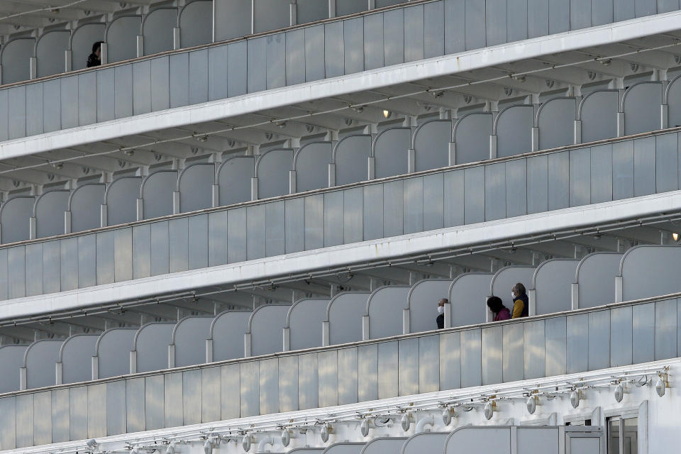 The passengers stand on the balcony of the quarantined Diamond Princess cruise ship docked at a port in Yokohama, near Tokyo, Wednesday, Feb. 19, 2020. The cruise ship begins letting passengers off the boat on Wednesday after it's been in quarantined for 14 days. (AP Photo/Eugene Hoshiko)