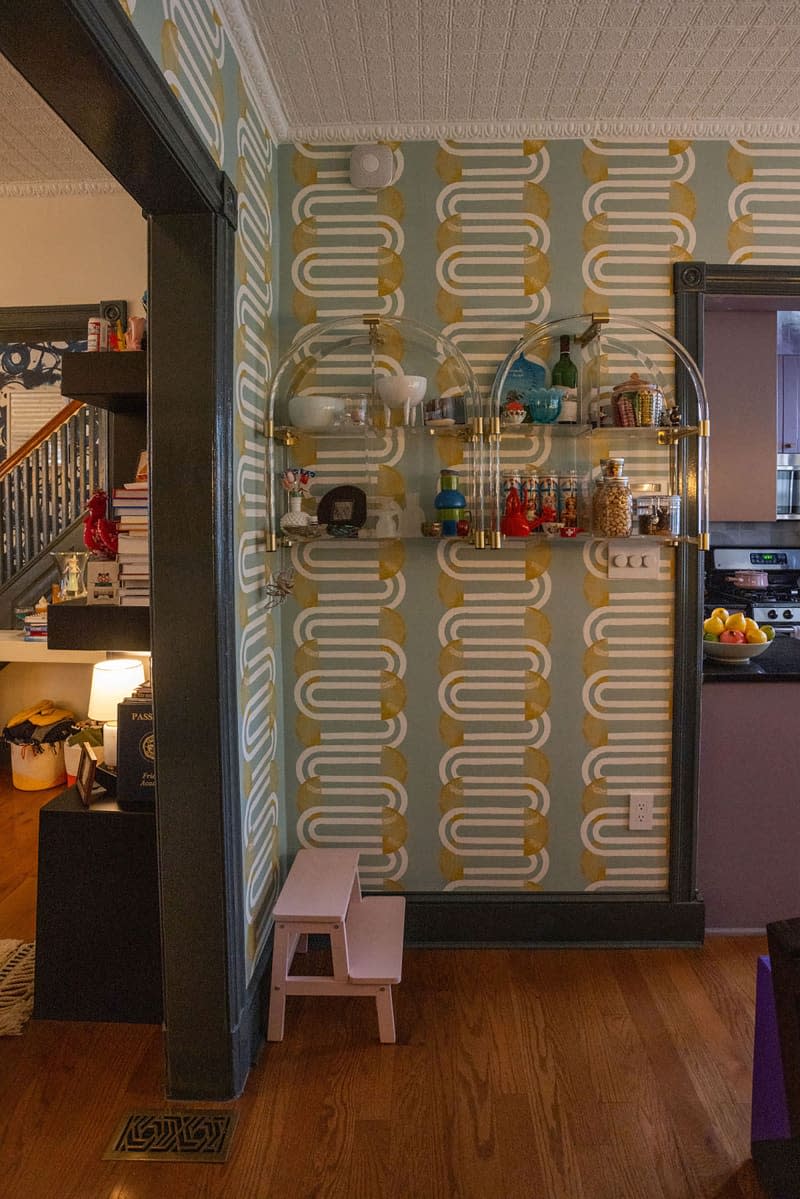 Barware on lacquer shelving beside kitchen.