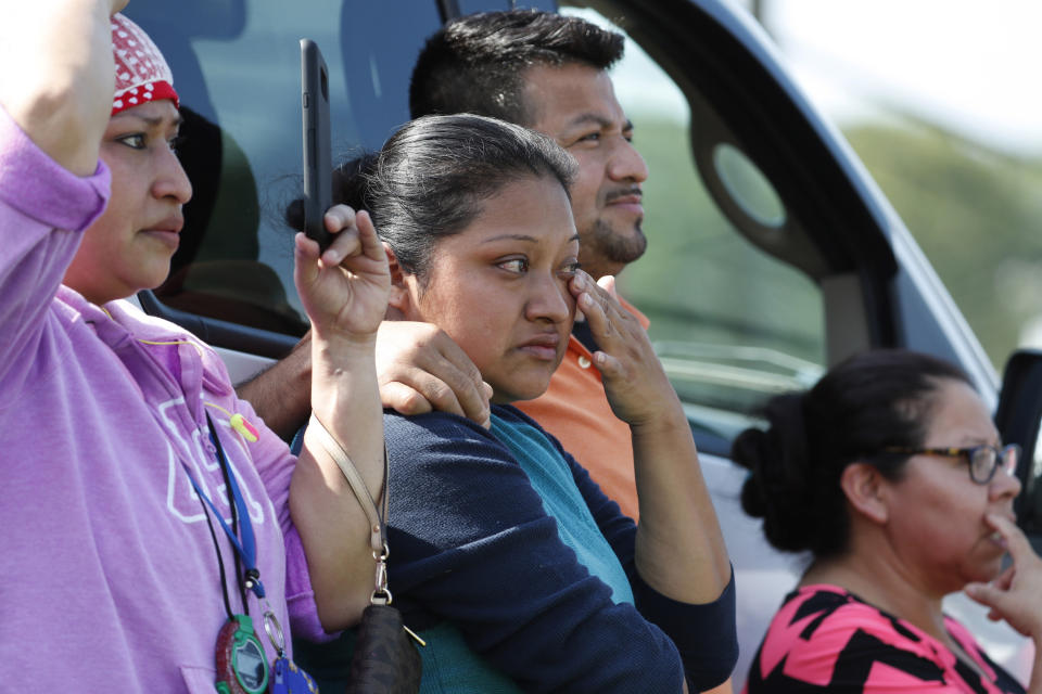 FILE - In this Aug. 7, 2019, file photo, Friends, coworkers and family watch as U.S. immigration officials raid the Koch Foods Inc., poultry processing plant in Morton, Miss. Federal officials announced Thursday, Aug. 6, 2020, the indictments of four executives from two Mississippi poultry processing plants on federal charges tied to one of the largest workplace immigration raids in the U.S. in the past decade. (AP Photo/Rogelio V. Solis, File)