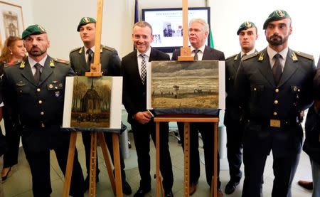Italian Guardia di Finanza officers stand next to paintings by the Dutch artist Vincent Van Gogh, that were stolen in Amsterdam 14 years ago, during a news conference in Naples September 30, 2016. REUTERS/Ciro De Luca