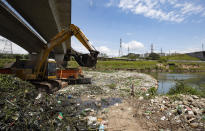 An excavator removes debris from the banks of the Pinheiros River in Sao Paulo, Brazil, Thursday, Oct. 22, 2020. Affected by domestic sewage and solid wastes discharges for years, Sao Paulo's state government is again trying to clean the Pinheiros River, considered one of the most polluted in Brazil. (AP Photo/Andre Penner)