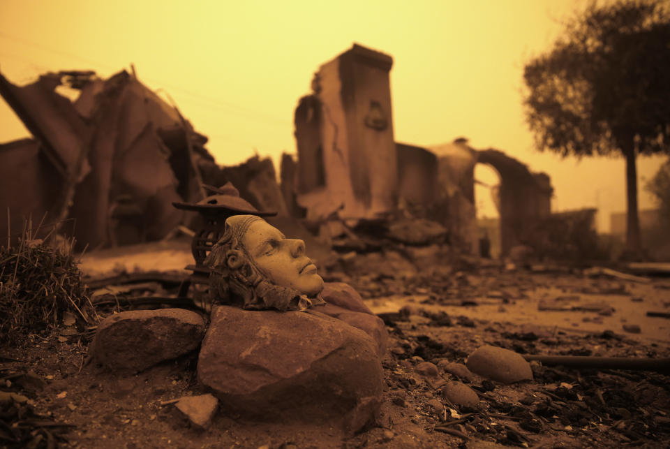 FILE - In this Nov. 9, 2018, file photo, a piece of art sits outside the burned remains of a home destroyed by the Camp Fire in Paradise, Calif. Only a handful of homes have been rebuilt in the community that lost nearly 9,000 residences in the wildfire. (AP Photo/Rich Pedroncelli, File)