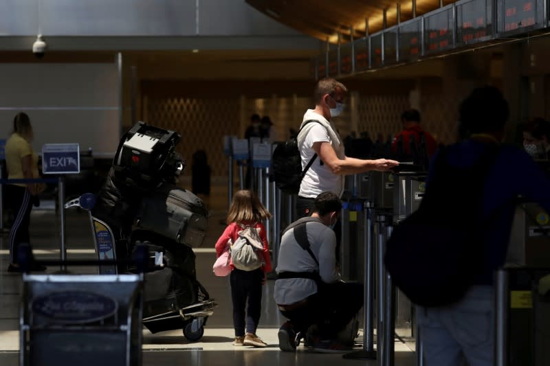 FILE PHOTO: Travelers check-in for a flight while wearing protective face masks at Los Angeles International Airport (LAX) on an unusually empty Memorial Day weekend during the outbreak of the coronavirus disease (COVID-19) in Los Angeles