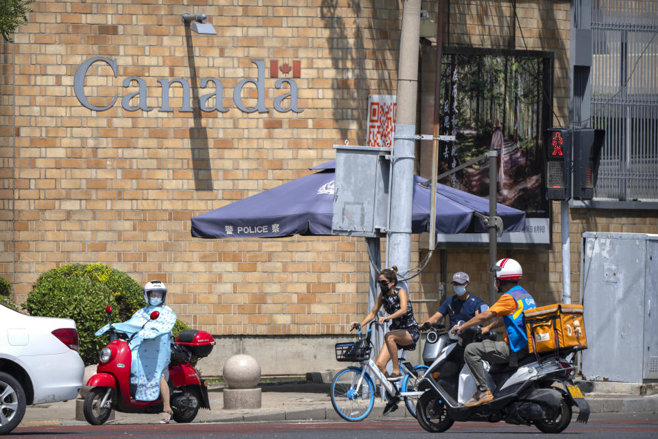 People wait to cross an intersection near of the Canadian Embassy in Beijing, Tuesday, Aug. 10, 2021. A Chinese court has rejected an appeal by a Canadian whose sentence in a drug case was increased to death after an executive of tech giant Huawei was detained in Vancouver. (AP Photo/Mark Schiefelbein)