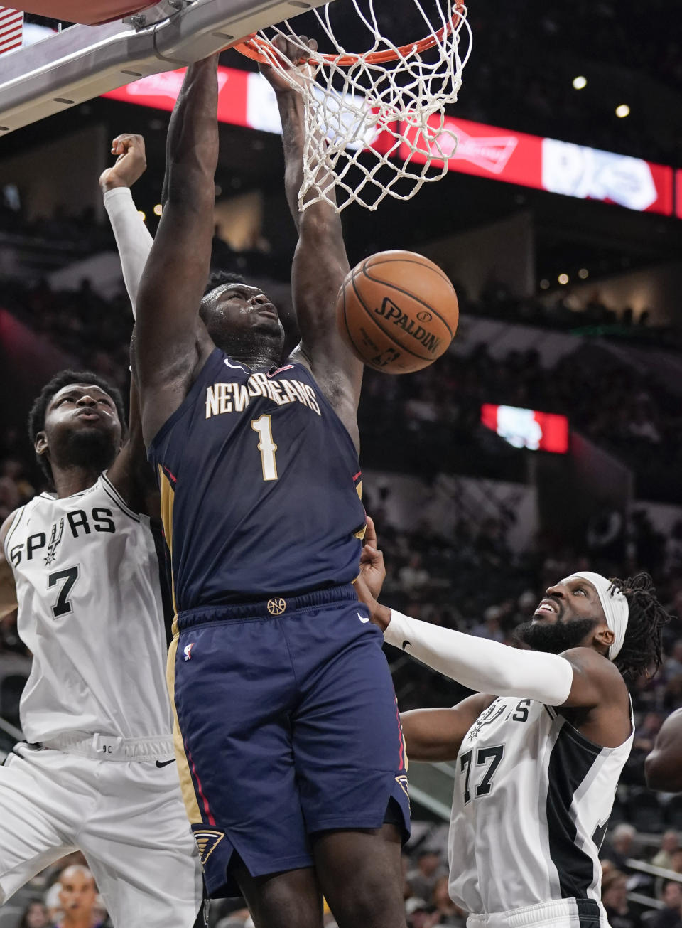 New Orleans Pelicans' Zion Williamson (1) dunks as he is defended by San Antonio Spurs' Chimezie Metu (7) and DeMarre Carroll during the first half of an NBA preseason basketball game, Sunday, Oct. 13, 2019, in San Antonio. (AP Photo/Darren Abate)