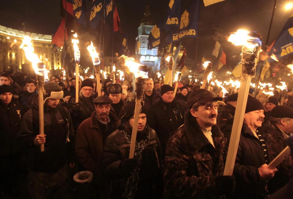 Ukrainian nationalists carry torches during a rally in downtown Kiev, Ukraine, late Wednesday, Jan. 1, 2014. The rally was organized on the occasion of the birth anniversary of Stepan Bandera, founder of a rebel army that fought against the Soviet regime and who was assassinated in Germany in 1959. (AP Photo/Sergei Chuzavkov)