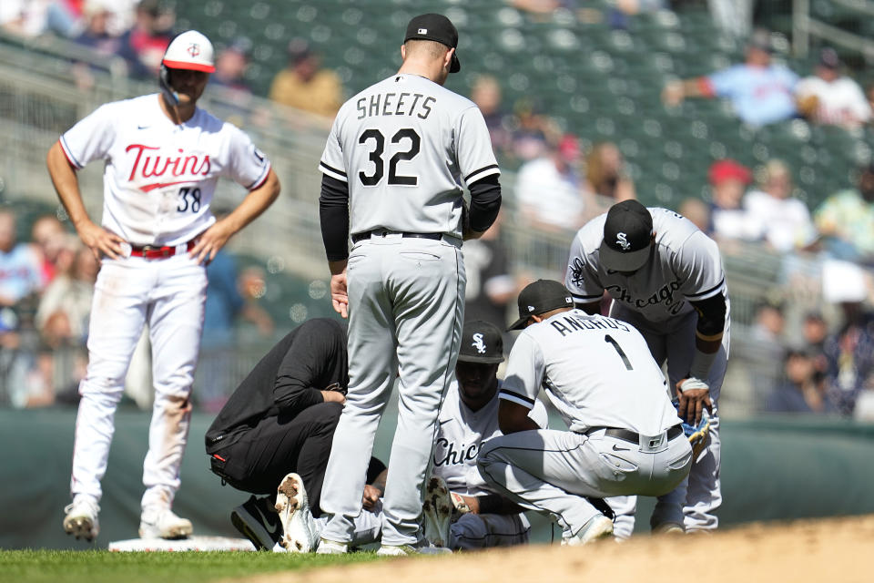 Chicago White Sox shortstop Tim Anderson, middle, is attended to after sustaining an injury from a collision with Minnesota Twins' Matt Wallner while covering third base during the fourth inning of a baseball game, Monday, April 10, 2023, in Minneapolis. (AP Photo/Abbie Parr)