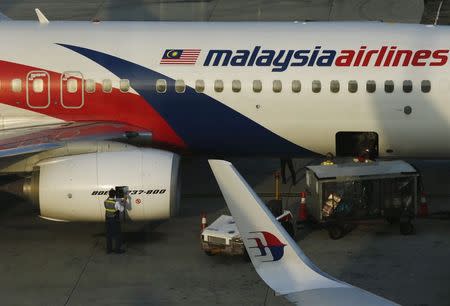 A member of ground crew works on a Malaysia Airlines Boeing 737-800 airplane on the runway at Kuala Lumpur International Airport in Sepang July 25, 2014. REUTERS/Olivia Harris