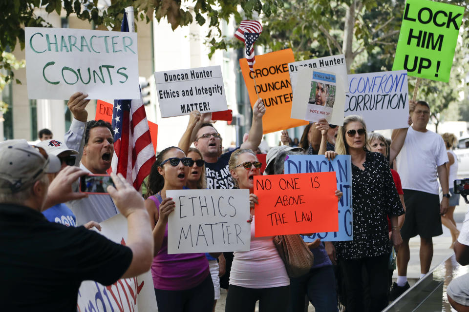 Protesters chant slogans as U.S. Rep. Duncan Hunter arrives for an arraignment hearing Thursday, Aug. 23, 2018, in San Diego. Hunter and his wife were indicted Tuesday on federal charges that they used more than $250,000 in campaign funds for personal expenses that ranged from groceries to golf trips and lied about it in federal filings, prosecutors said. (AP Photo/Gregory Bull)