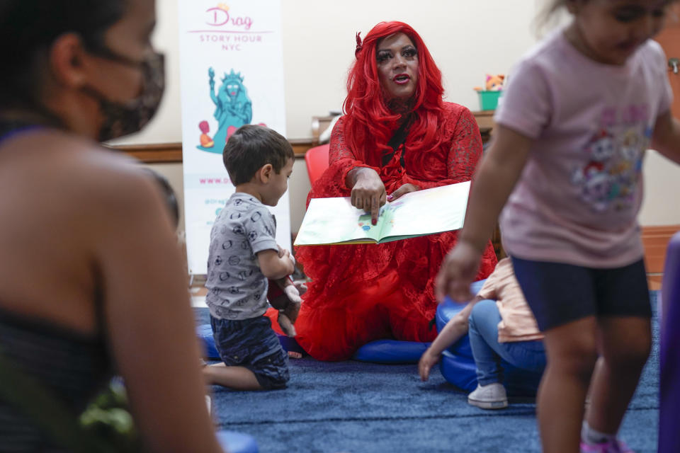 A drag queen who goes by the name Flame reads stories to children and their caretakers during a Drag Story Hour at a public library in New York, Friday, June 17, 2022. (AP Photo/Seth Wenig)