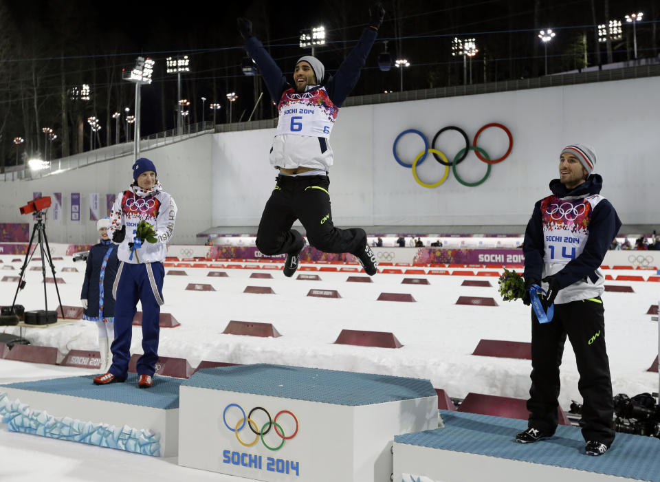 Gold medal's winner France's Martin Fourcade, center, jumps in celebration flanked by with silver medalist Czech Republic's Ondrej Moravec, left, and bronze medalist France's Jean Guillaume Beatrix, during the flowers ceremony for the men's biathlon 12.5k pursuit, at the 2014 Winter Olympics, Monday, Feb. 10, 2014, in Krasnaya Polyana, Russia. (AP Photo/Kirsty Wigglesworth)