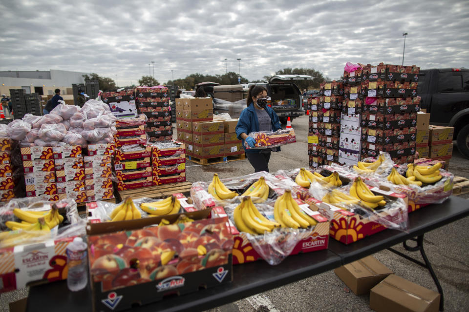 A volunteer carries food to be distributed during the Neighborhood Super Site food distribution event organized by the Houston Food Bank and HISD, Sunday, Feb. 21, 2021, in Houston. (Marie D. De Jesús/Houston Chronicle via AP)