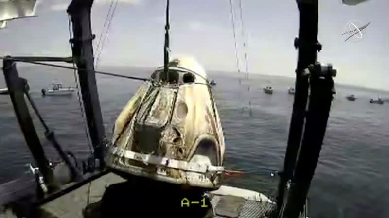 A capsule with NASA astronauts Robert Behnken and Douglas Hurley is lifted out of water in the Gulf of Mexico