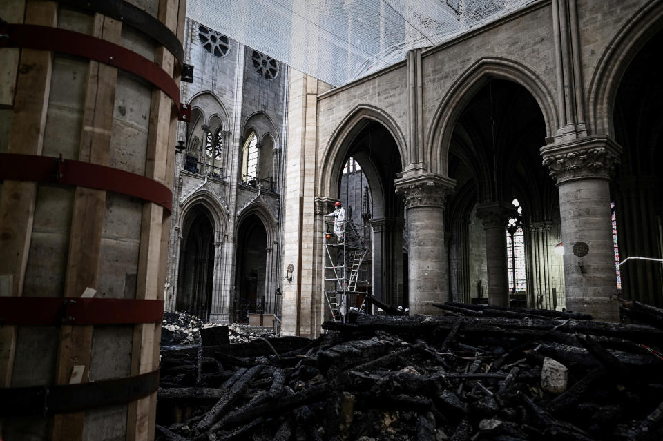 FiILE - A worker stands on scaffolding during preliminary work inside the Notre Dame de Paris Cathedral, Wednesday May 15, 2019 in Paris. France's Notre Dame Cathedral's reconstruction is progressing enough to allow its reopening to visitors and masses at the end of next year, less than six years after the after the shocking fire that tore through its roof, French officials said as an exhibit pays tribute to hundreds of artisans working on it.(Philippe Lopez/Pool via AP, File)