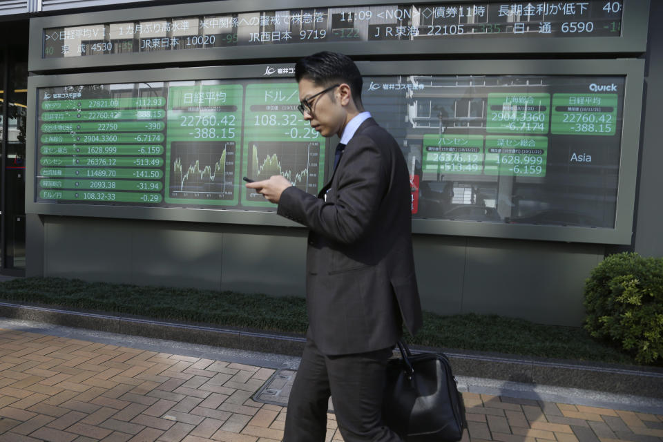 In this Thursday, Nov. 21, 2019, photo, a man walks by an electronic stock board of a securities firm in Tokyo. Stocks logged modest gains Friday, Nov. 22, 2019, in Asia after a lackluster overnight session on Wall Street ended with the market’s third straight drop. (AP Photo/Koji Sasahara)