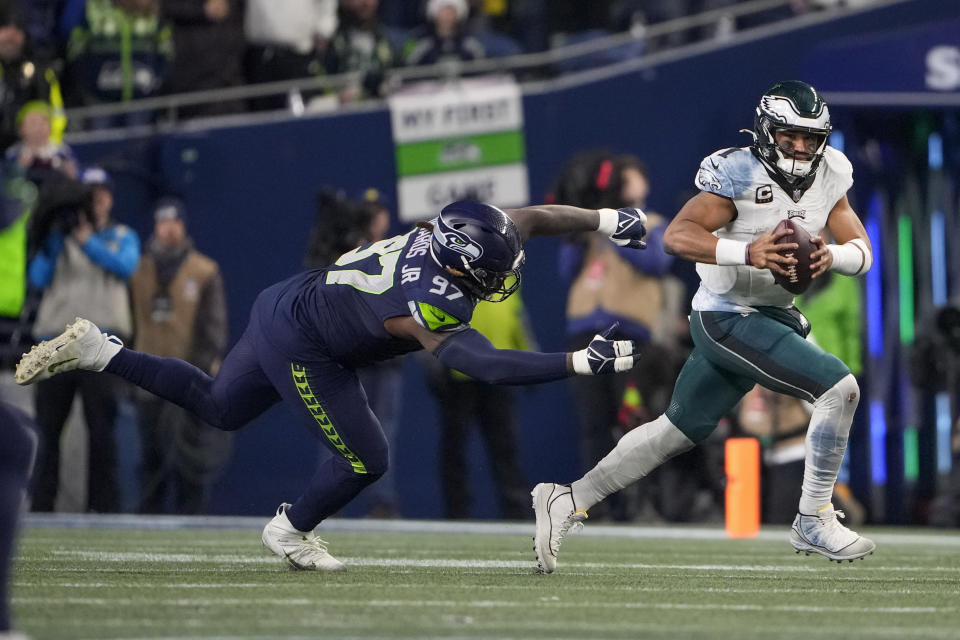 Philadelphia Eagles quarterback Jalen Hurts, right, runs for yardage as Seattle Seahawks defensive end Mario Edwards Jr. (97) tries to stop him during the first half of an NFL football game, Monday, Dec. 18, 2023, in Seattle. (AP Photo/Lindsey Wasson)