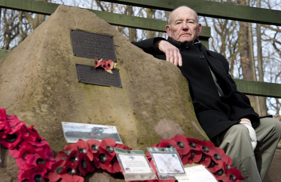 Tony Foulds sits next to a memorial honouring 10 U.S. airmen who died in a plane crash in Endcliffe Park, Sheffield, England, Wednesday, Feb. 13, 2019. Foulds was just a kid running around in the park on Feb. 22, 1944 when a U.S. Air Force crew decided to crash and die rather than take the chance of hitting them. He's dreamed of honoring them for decades. Now he's 82 and about to get his wish. (AP Photo/Rui Vieira)