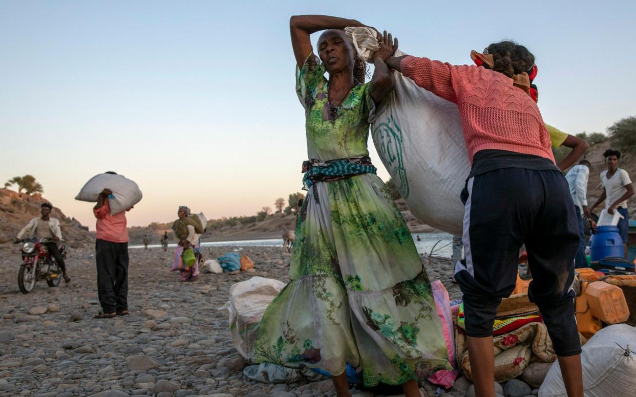 Tigray refugee women help each other carry their belongings after they arrive on the banks of the Tekeze River on the Sudan-Ethiopia border, in Hamdayet - Nariman El-Mofty /AP