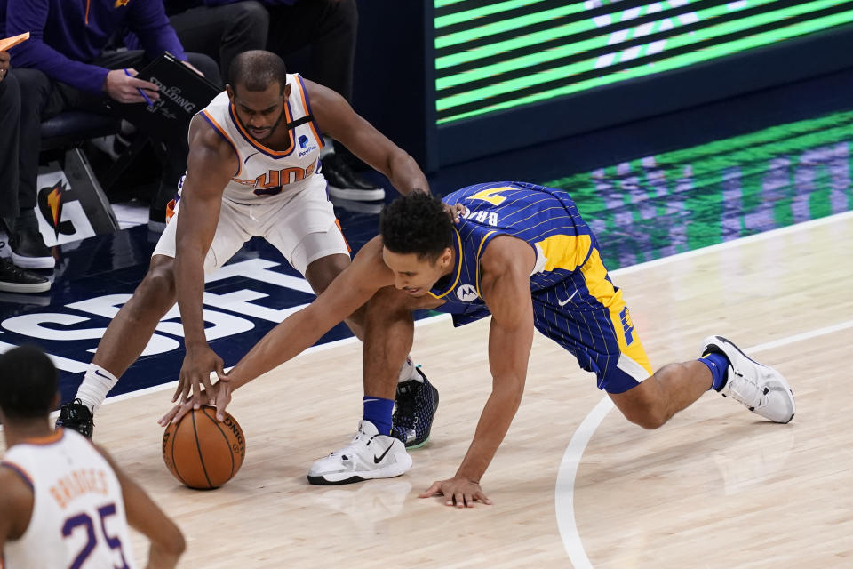 Indiana Pacers guard Malcolm Brogdon (7) and Phoenix Suns' Chris Paul (3) battle for the ball during the second half of an NBA basketball game, Saturday, Jan. 9, 2021, in Indianapolis. (AP Photo/Darron Cummings)