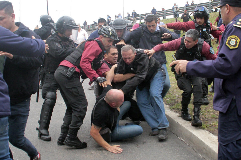 Sergio Berni, the security minister for the Buenos Aires province, center right, is separated from an attacker, below, during a protest in Buenos Aires, Monday, April 3, 2023. Berni was attacked during a protest by bus drivers after the murder of a co-worker while on the job. (AP Photo/Andres Pelozo)