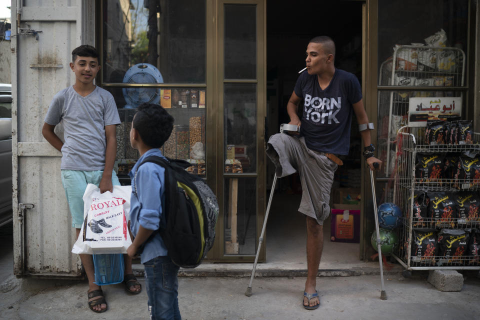 In this Sept. 16, 2018 photo, Atalla Fayoumi, smokes a cigarette outside a shop near his house in Gaza City. The 18-year-old Palestinian's right leg was amputated after Israeli soldiers shot him in April at a mass demonstration held weekly for the past six months against Israel's long siege of Gaza. Yet, like other desperate young men in Gaza who feel they have nothing left to lose, he has kept returning to the protests -- which many fear are pushing the region toward the brink of another war. (AP Photo/Felipe Dana)