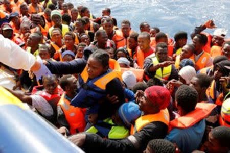 Migrants in a dinghy climb aboard the Migrant Offshore Aid Station (MOAS) ship Topaz Responder around 20 nautical miles off the coast of Libya, June 23, 2016. Picture taken June 23, 2016.REUTERS/Darrin Zammit Lupi