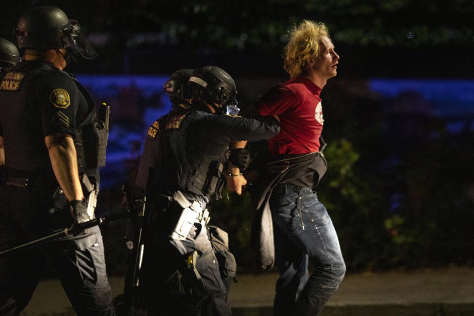 Portland police make arrests on the scene of the nightly protests at a Portland police precinct on Sunday, Aug. 30, 2020 in Portland, Ore. Oregon State Police will return to Portland to help local authorities after the fatal shooting of a man following clashes between President Donald Trump supporters and counter-protesters that led to an argument between the president and the city's mayor over who was to blame for the violence. (AP Photo/Paula Bronstein)