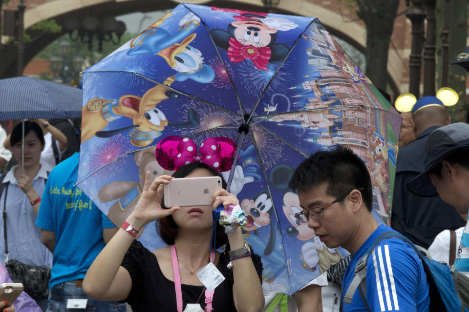 A woman takes photo on her phone during the opening day of the Disney Resort in Shanghai, China, Thursday, June 16, 2016. Walt Disney Co. opened its first theme park in mainland China on Thursday at a ceremony that mixed speeches by Communist Party officials, a Chinese children's choir and actors dressed as Sleeping Beauty and other Disney characters. (AP Photo/Ng Han Guan)