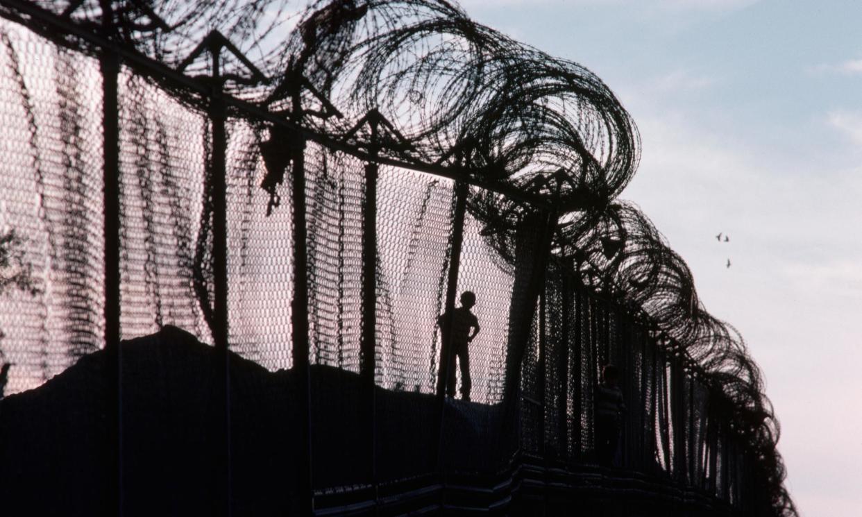 <span>A child runs along the US-Mexico border fence in Calexico, California.</span><span>Photograph: Stephanie Maze/Getty Images</span>