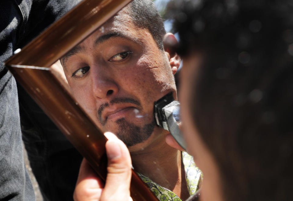 A Central American migrant trims his facial hair in a shelter at the Jesus Martinez stadium in Mexico City, Tuesday, Nov. 6, 2018. Humanitarian aid converged around the stadium in Mexico City where thousands of Central American migrants winding their way toward the United States were resting Tuesday after an arduous trek that has taken them through three countries in three weeks. (AP Photo/Marco Ugarte)