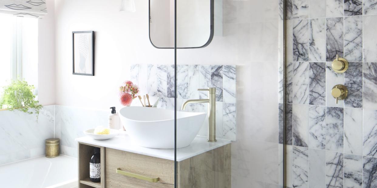 a family bathroom in a neutral colour palette featuring brass hardware and veined marble tiles