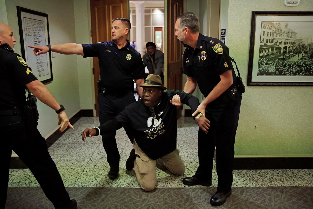 Community and civil rights activist Ben Frazier is detained by police during city council meeting Tuesday, Dec. 13, 2022 at City Hall in Jacksonville. Frazier would not yield after his public comments seconds were up and was arrested on trespassing with a warning and resisting arrest. He kept telling police officers, "I am not resisting arrest," before being taken away in a police SUV. The Northside Coalition, NAACP, Florida Rising and other groups protested over Confederate monument statues ahead of the meeting at 5pm. During his time at the microphone he began chanting, "Take them down," repeatedly, toward the council, and those in attendance. 