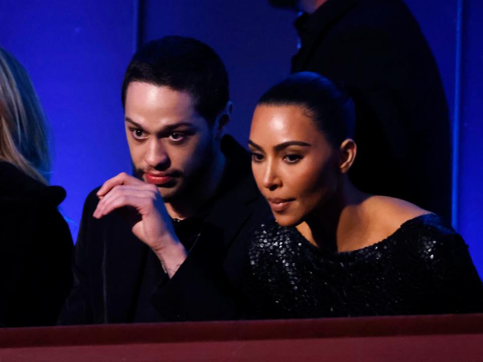 Pete Davidson and Kim Kardashian sit in the audience, leaning forward with anticipation