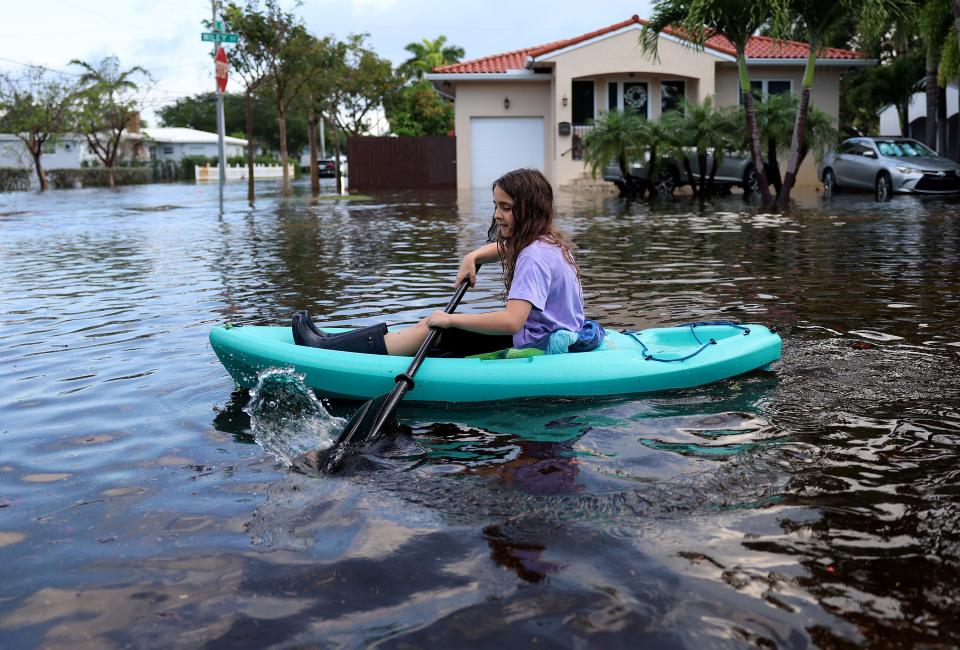 Martina Spiering kayaks through a flooded street after record rains fell in the area on April 13, 2023 in Hollywood, Florida.