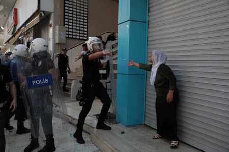 Demonstrators react as police try to disperse them during a protest against the replacement of Kurdish mayors with state officials in three cities, in Diyarbakir