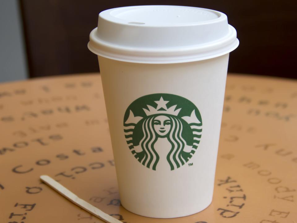 Starbucks coffee cup on a table with type-face design and a stirrer