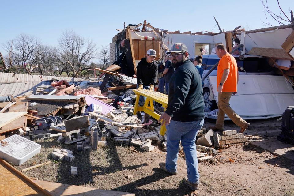 Adam Lee left, and Jr. Ibarra, right, carry a table from a friend's home after it was destroyed by a tornado Dec. 13, 2022, in Wayne, Okla. The state is one of ten disaster-prone states the federal government is requesting insurance information from.