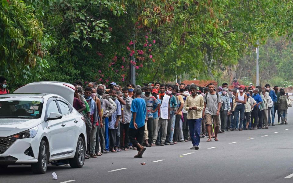 Homeless people mostly working as daily wage labourers and are out of jobs due to the lockdown queue as volunteers distribute food along the roadside - Prakash SINGH / AFP