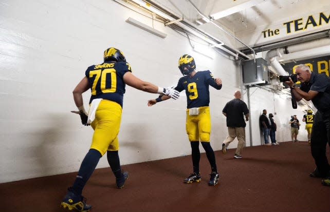 Peter Simmons III high-fives Michigan starting quarterback JJ McCarthy pregame