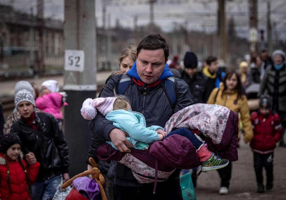 A man carrying a little girl arrives with other families to board a train as they flee the eastern city of Kramatorsk in the Donbas region of Ukraine on April 4.