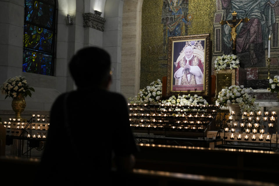 A devotee offers a prayer in front of a portrait of the late Pope Emeritus Benedict XVI at the Manila Cathedral, Philippines, in this predominantly Roman Catholic nation on Tuesday, Jan. 3, 2023. (AP Photo/Aaron Favila)